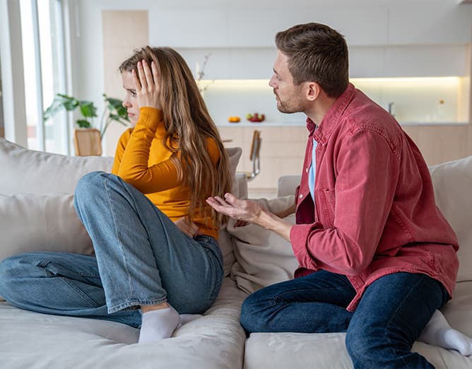 A couple sitting apart on a sofa
